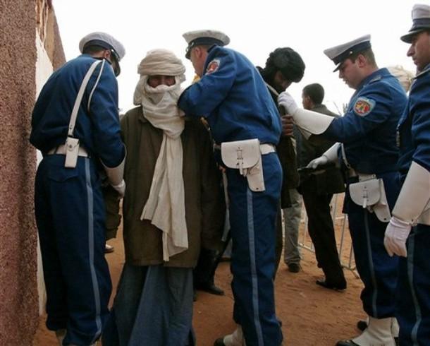 Policemen, left, center and right, search Touareg men wishing