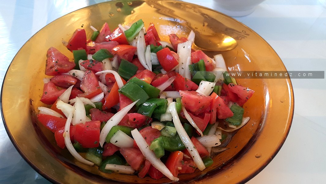Une salade de tomates, poivrons, oignons, vinaigre, huile d'olive et basilic