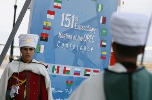 Honour guards stand next to an OPEC poster before