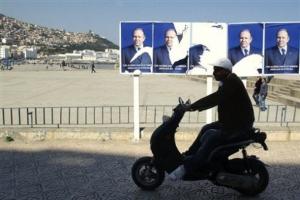 A man rides a scooter pas electoral posters for outgoing