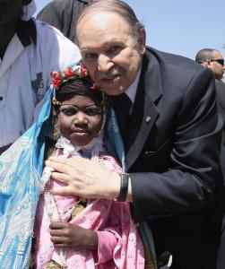 Algeria's President Abdelaziz Bouteflika (R) poses with a girl dressed