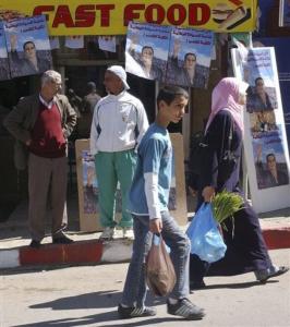 Residents walks past campaign posters of Trotskyite candidate to the
