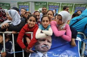 Algerian young girls stand in front of a placard with