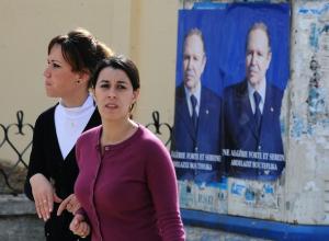 Algerian girls walk past posters of President Abdelaziz Bouteflika during