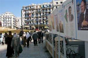 People walk past campaign posters of some of the candidates