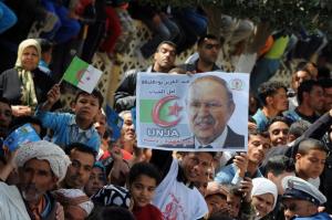 Algerians wave national flags and carry posters of President Abdelaziz