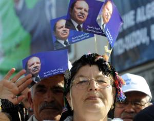 An Algerian woman holds flags showing President Abdelaziz Bouteflika during
