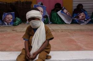 An Algerian child sits next to posters of Algeria's President