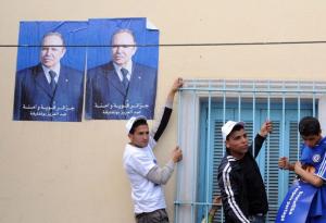 Algerian men stand underneath posters of President Abdelaziz Bouteflika during