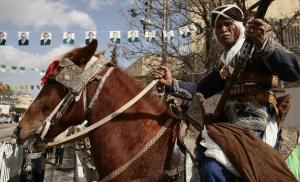 A horse rider dressed in traditional robes poses during the