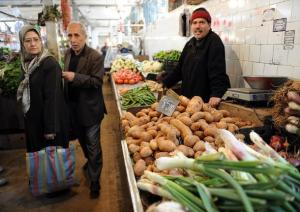 Algerians look at the prices of vegetables at a market
