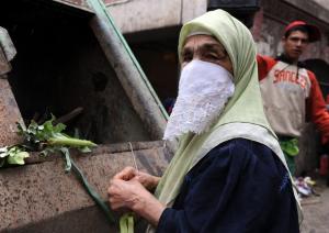 An Algerian woman looking for food in a market garbage
