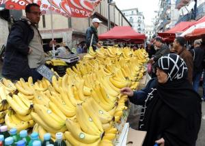 Algerians look at the price of bananas at a market