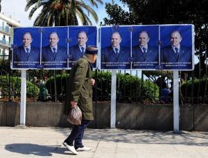 An elderly resident walks in front of posters showing President