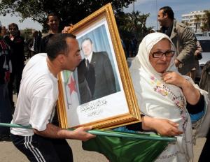 An Algerian man kisses a placard portraiting Algeria's President Abdelaziz