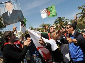 Algerians hold up placards and national flags during a gathering