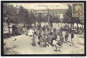 CPA  ANCIENNE- TUNISIE- SOUK-AHRAS  PLACE TRAGASTE AVEC TRES BELLE ANIMATION GROS PLAN- COLONNE AVEC STATUE-