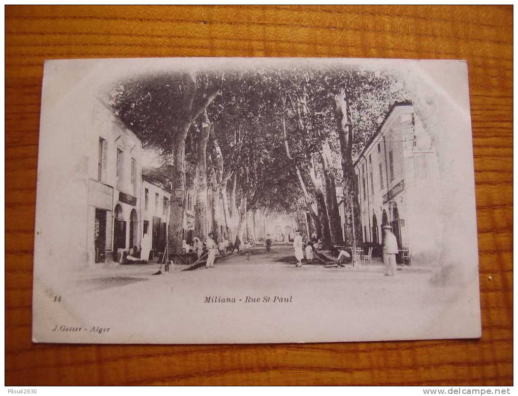 carte précuseur de le Rue St Paul de Miliana  le cantonnier balaie devant les magasins  . Algérie