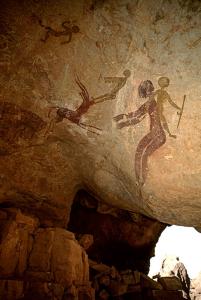 Djanet, Algérie. A droite, femme avec des seins et le corps bien décoré et les jambes, détient bâton, progrès droite, superposée à personne la tête baissée et les bras face à gauche.