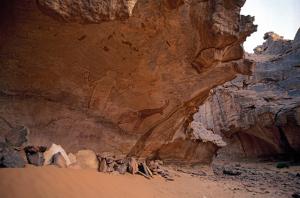 Djanet, Algérie. Peinture de la figure mythique et l\'antilope. D\'autres peintures fanées des personnes et des antilopes visibles.
