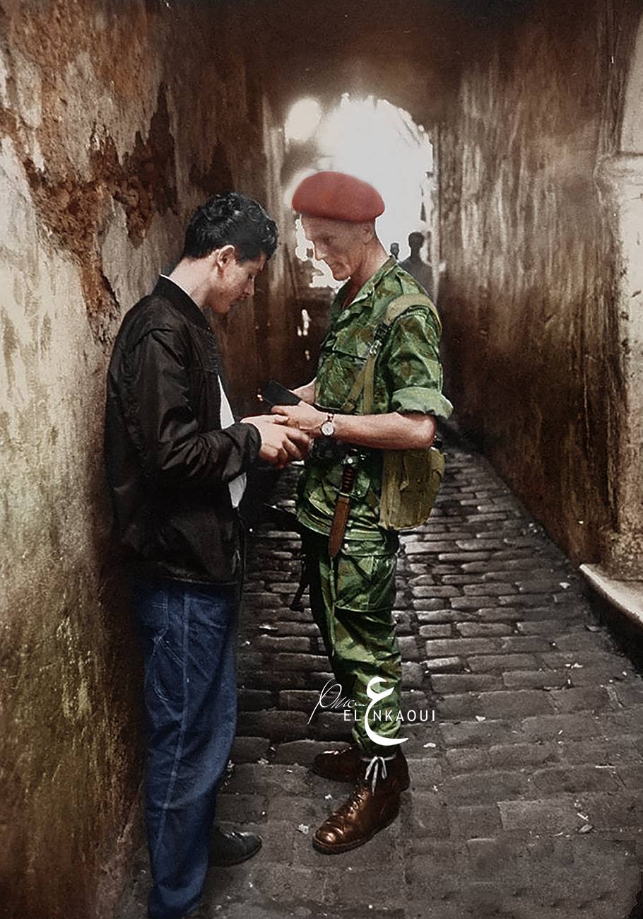 جندي فرنسي يفتش شاب جزائري في أحد الأزقة