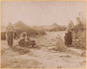 [Tentes près de Biskra : femmes préparant la galette accompagnées d'enfants] (Photo rare)