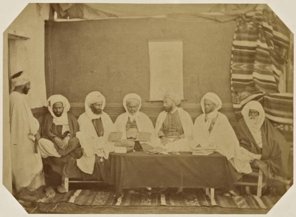 Midjelès d'Oran. [de gauche à droite]  Si Mohammed ben El Hadj Hassen, amin des Berrani, Si Abd-El-Kader El Fetouhi, adel, Si Adda ben Arriba, cadhi des douars, Si Mohammed Bel Gaïd, cadhi d'Oran, Si Hamida ben El Caid Omar, muphti d'Oran, président, Si M (Photo rare)