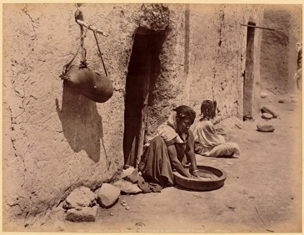 Sahara algérien. Négresse pétrissant la galette dans la guessâa (Photo rare)