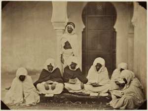 Midjelés de Mascara. Si Mohammed ben Machou, bach-adel taleb alem. Si Tahar Ben Amar, juge, taleb alem. Si Taieb ben Moktar, juge, cadhi de la 48ème circonscription. Si Tahar El Mahfoudi, président, taleb alem. Si Mohammed B en Mokhtar , juge taleb alem. Si Mahi Ben Machou, adel taleb. Un chaouch en arrière du groupe (Image de propagande coloniale)