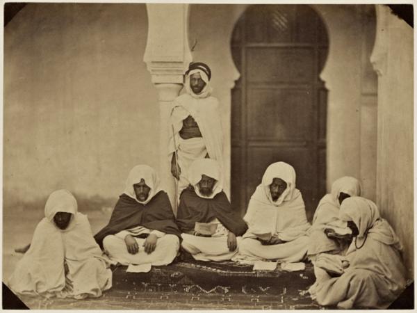 Midjelés de Mascara. Si Mohammed ben Machou, bach-adel taleb alem. Si Tahar Ben Amar, juge, taleb alem. Si Taieb ben Moktar, juge, cadhi de la 48ème circonscription. Si Tahar El Mahfoudi, président, taleb alem. Si Mohammed B en Mokhtar , juge taleb alem. Si Mahi Ben Machou, adel taleb. Un chaouch en arrière du groupe (Image de propagande coloniale)