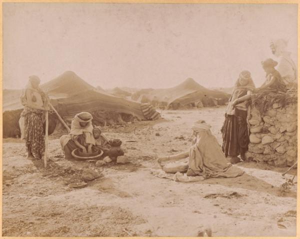 [Tentes près de Biskra : femmes préparant la galette accompagnées d'enfants] (Image de propagande coloniale)