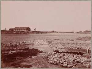 Port-aux-Poules. A droite, tuyautage en plein air. Au-dessus et dans le fond, le forage. Sur le même plan et au millieu, tonneaux d'eau minérale, à déstination de l'Angleterre (savon spécial Seilma) (Image de propagande coloniale)