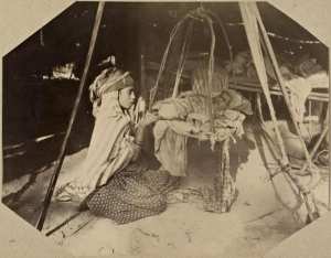 [Campement dans la région de Biskra : fillette surveillant un nourrisson] (Image de propagande coloniale)