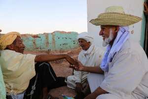 Trois vieillards discutent devant un mausolée : gardiens de l’histoire des saints