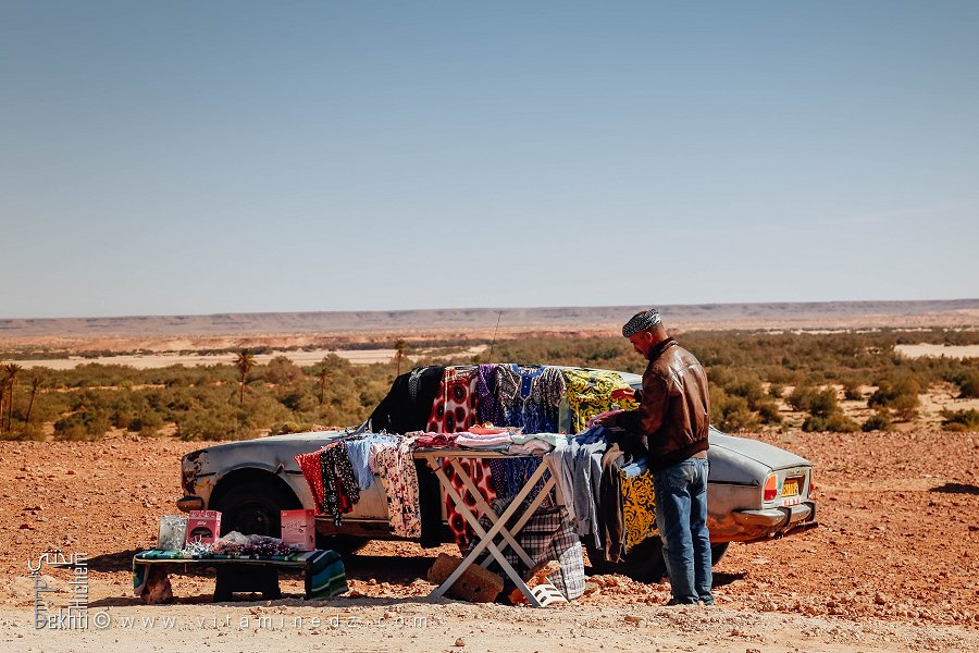 Vendeur de vêtements seul avec sa voiture dans l'immensité du désert : l'isolement et la détermination