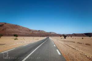 Route interminable et déserte entre reliefs nommés du Sahara occidental algérien