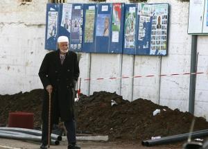An elderly Algerian walks past municipal electoral posters in