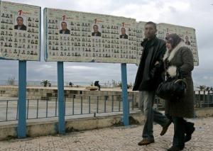 An Algerian couple walks past municipal electoral posters in