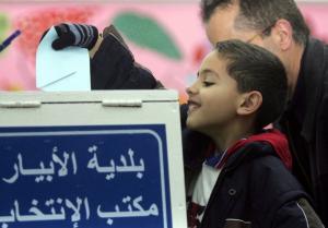 An Algerian boy casts a ballot for his father