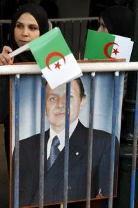 Algerian girls hold national flags and a portrait of