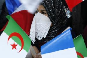 Algerian girls hold national flags and a portrait of