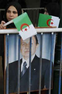 Algerian girls hold Algerian flags and a portrait of
