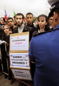 A student sporting a placard stands against mobile barriers