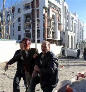 Rescuers support an injured man from the site of