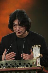 South Korean director Jeon Soo-il (L) speaks after receiving