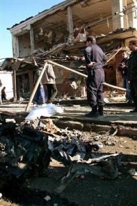 A policeman stands by a seriously damaged building in