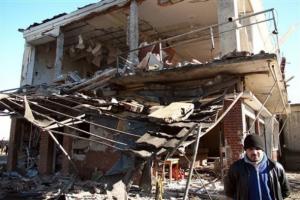 A man stands by a seriously damaged building in