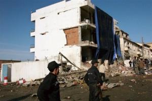 Policemen stand by the seriously damaged building of the