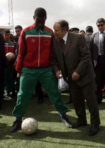 Algeria's President Abdelaziz Bouteflika jokes with a soccer player