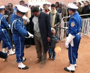 Policemen, left and right, search people wishing to attend